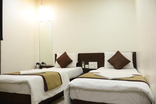 two beds sitting next to each other in a room at Hotel Kabir in Ahmedabad