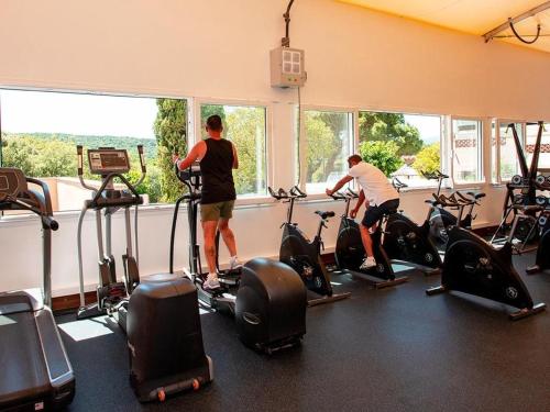 2 personnes faisant de l'exercice sur des vélos d'exercice dans une salle de sport dans l'établissement Mobil-home Parc Montana Gassin, à Gassin