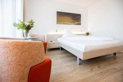 a bedroom with a bed and a table and a chair at Mercure Chur City West in Chur