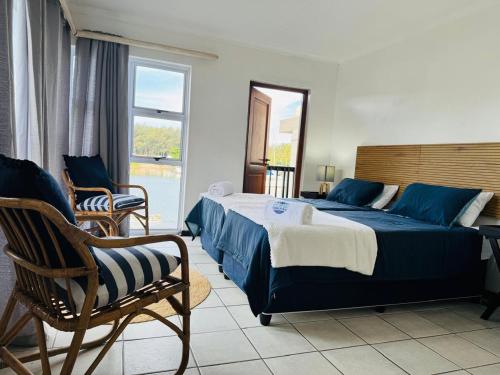 a bedroom with a bed and a chair and a window at Mzingazi Waterfront Accommodation, On The Bay Waterfront Villa's in Richards Bay