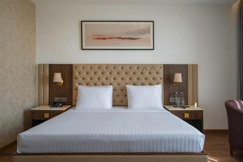 a bedroom with a large bed with two night stands and two lamps at Clarks Inn Dehradun in Dehradun