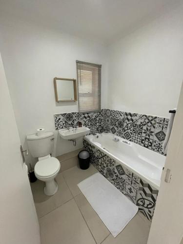 a bathroom with a toilet and a tub and a sink at 9 Dolphin Bay, Aston Bay in Jeffreys Bay