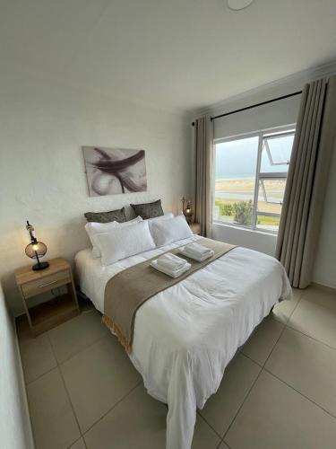 a bedroom with a large bed with a large window at 9 Dolphin Bay, Aston Bay in Jeffreys Bay