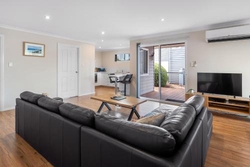 a living room with a black leather couch at Surfs Up in Dunsborough