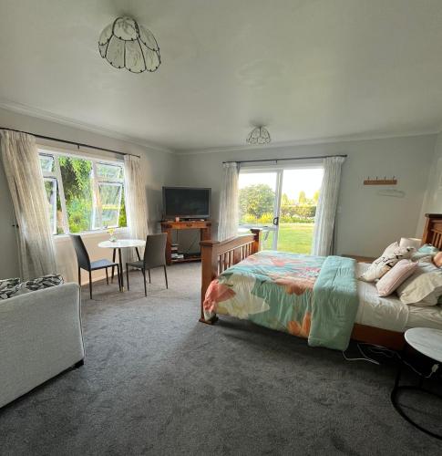 a bedroom with a bed and a living room with a table at Kaimai Sunset Bed & Breakfast in Matamata