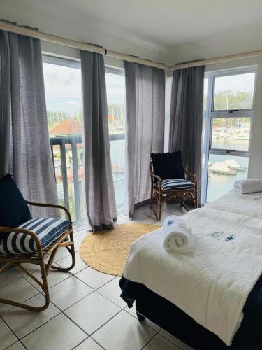 a bedroom with a bed and chairs and a balcony at Mzingazi Waterfront Accommodation, On The Bay Waterfront Villa's in Richards Bay