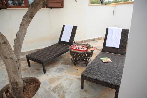 a patio with two chairs and a table and a tree at Bono Vacanze Villa San Marco Luxury Holidays Homes in Sciacca