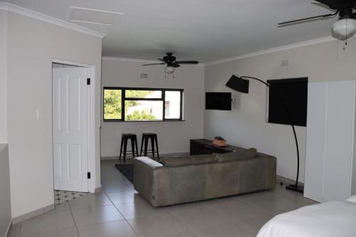 a living room with a couch and a tv at Villa Des Roses in Paarl