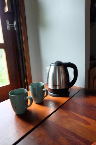 two cups on a wooden table with a tea kettle at Rawi Seaside Cottage, Ko Yao Noi in Ban Laem Sai