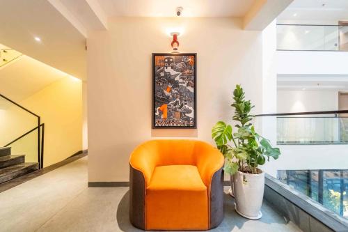 an orange chair in a hallway with a plant at Vilmaris Luxe Hotel, Calangute in Calangute