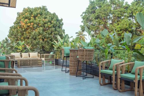 a patio with chairs and tables and trees at Vilmaris Luxe Hotel, Calangute in Calangute