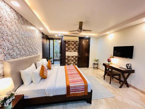 a bedroom with a bed and a desk and a television at South Haven Residency - South Extension South Delhi in New Delhi