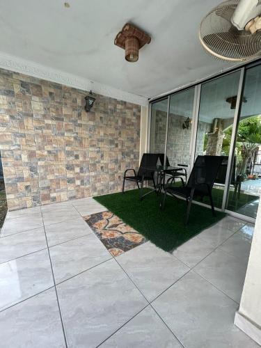 a patio with two chairs and a table and a brick wall at Double Storey Terrace House in Perai