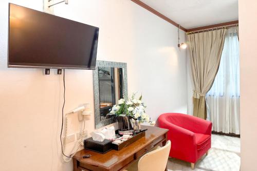 a living room with a red chair and a flat screen tv at Chiangmai Lanna & Modern Loft Hotel in Ban Mae Pu Kha