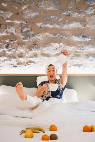 a young child laying on a bed with a bowl of food at Maison des Cassiers By Les Fleurines in Villefranche-de-Rouergue