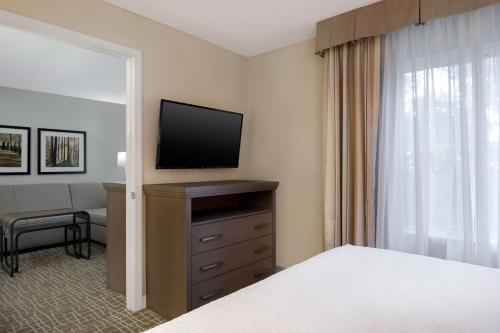 a hotel room with a bed and a flat screen tv at Homewood Suites by Hilton Tallahassee in Tallahassee