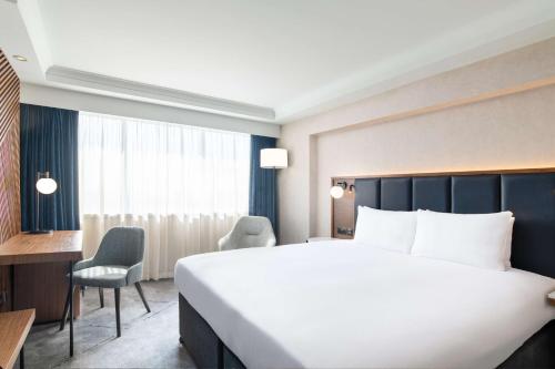 a bedroom with a large bed and a desk and chairs at Hilton London Metropole in London