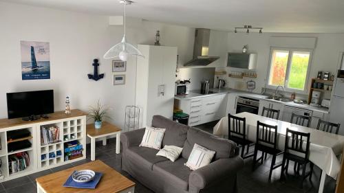 un salon avec un canapé et une cuisine dans l'établissement Gite du Corps de Garde - Bord de Mer Normandie, à Saint-Germain-sur-Ay
