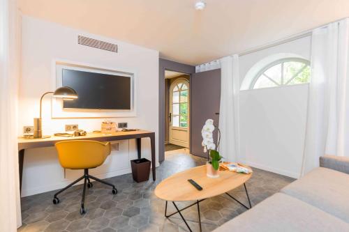 a room with a desk and a bed and a table at Dolce by Wyndham Versailles - Domaine du Montcel in Jouy-en-Josas