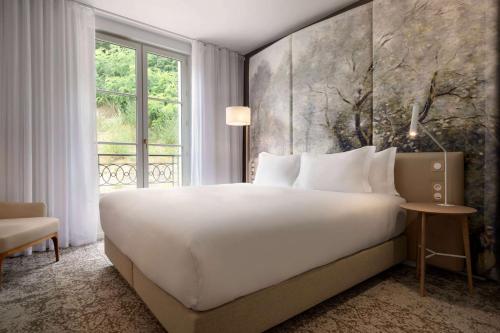 a bedroom with a large white bed and a window at Dolce by Wyndham Versailles - Domaine du Montcel in Jouy-en-Josas