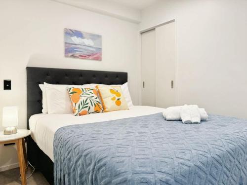 a bedroom with a large bed with a blue blanket at Central Location Cozy Studio with Pool Gym & Sauna Nearby Skytower in Auckland