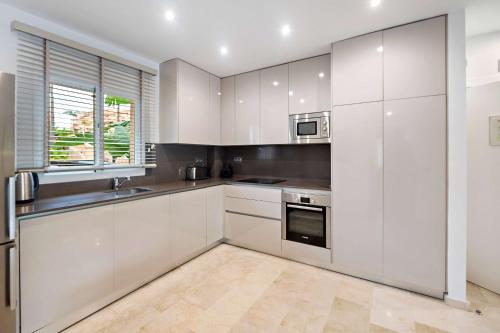 a kitchen with white cabinets and a sink at Wyndham Grand Costa del Sol in Mijas Costa