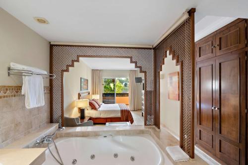 a bathroom with a tub and a bedroom at Wyndham Grand Costa del Sol in Mijas Costa