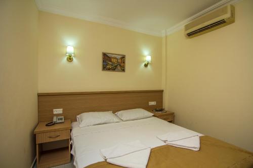 a bedroom with a white bed and a desk and lights at Hotel Karbel Sun in Oludeniz