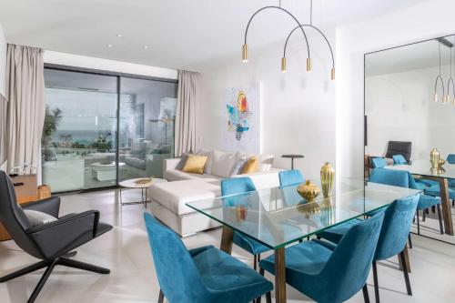 a living room with a glass table and blue chairs at Wyndham Grand Costa del Sol in Mijas Costa