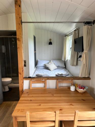 a room with a bed and a wooden table and chairs at Vicarage Hideaways in Halvergate