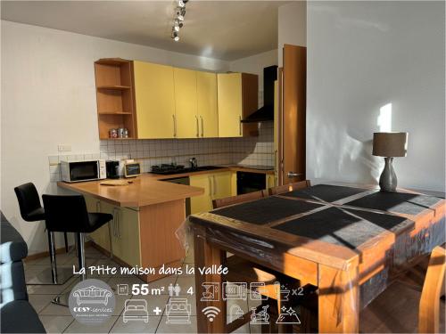 d'une cuisine avec des armoires jaunes et une table. dans l'établissement LaPetite Maison dans la vallée, à Hayange