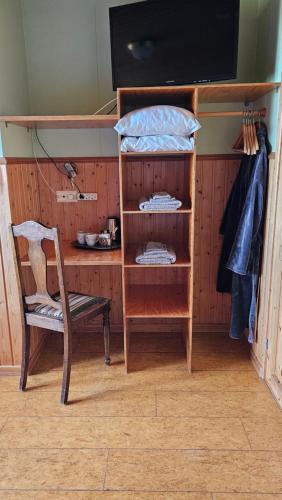 a room with a chair and a shelf and a television at Árnanes Country Hotel in Höfn