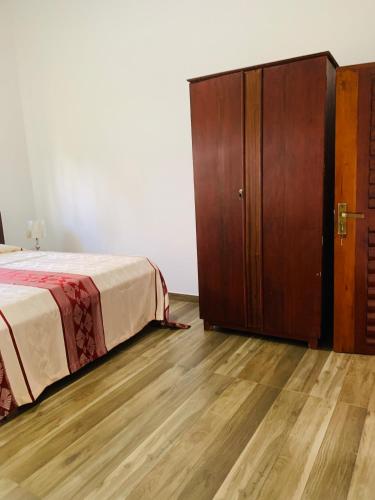 a bedroom with a bed and a wooden cabinet at Malinga homes in Wennappuwa