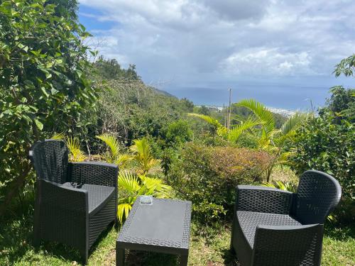 two chairs and a table with a view of the ocean at Les Chalets de marie 2 - Vue mer, Jacuzzi SPA privatif dans le chalets Sans vis à vis in Saint-Denis