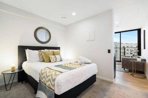 a bedroom with a bed and a mirror on the wall at High Level Stylish Studio Apartment City Central - Pool Gym Sauna in Auckland