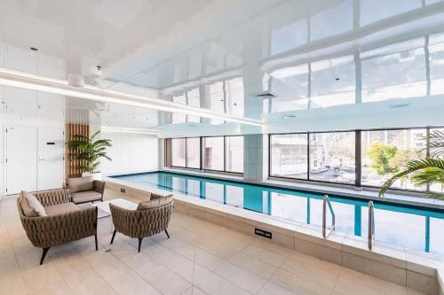 a swimming pool in a large building with a large window at High Level Stylish Studio Apartment City Central - Pool Gym Sauna in Auckland