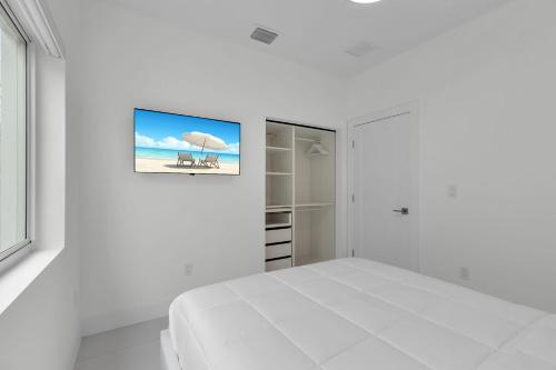 a white bedroom with a bed and a painting on the wall at Azul Paradise - Waterfront - Heated Pool - Dock in Marathon