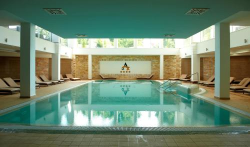 una gran piscina en un edificio con sillas en Hotel Atlantis Medical, Wellness & Conference, en Hajdúszoboszló