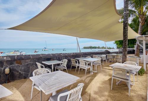 a restaurant with tables and chairs and the ocean at Le Beachclub in Pereybere