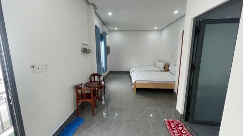 a small room with a bed and a table and chairs at Nhà Nghỉ Dragon in Cao Lãnh
