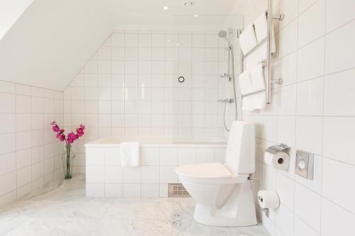 a white bathroom with a toilet and a bath tub at Elite Stadshotellet Västerås in Västerås