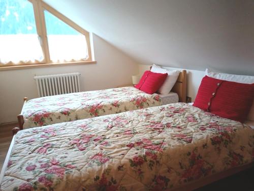 a bedroom with two beds with red pillows at Appartamento 2 Residenza RODODENDRO in Campitello