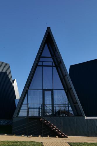 a building with a triangular roof with glass at Green Village Pensiune in Roşu