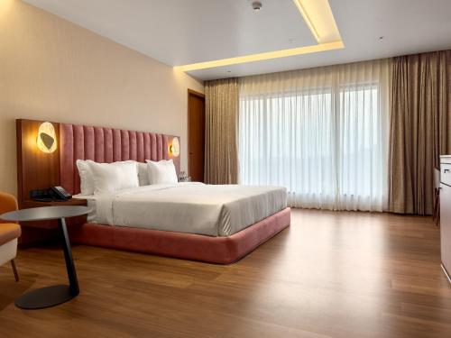 a hotel room with a large bed and a table at Royal Ritis in Belgaum