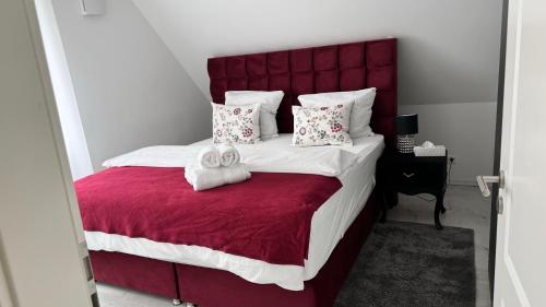a bedroom with a large bed with a red headboard at RelaxDays-Apartments 2 GARTEN und POOL- Mitbenutzung, kostenloser Parkplatz, kontaktloser CheckIn, WiFi mit SmartTV in Gütersloh