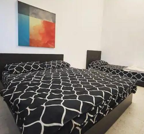 ein schwarz-weißes Bett in einem Schlafzimmer mit einem Gemälde in der Unterkunft LSH Homestay in Seremban