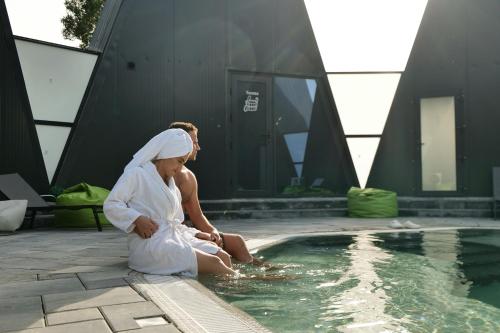 a woman in a white robe sitting next to a swimming pool at Green Village Pensiune in Roşu