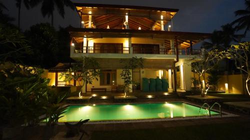 a villa with a swimming pool in front of a house at OMA Hikkaduwa in Hikkaduwa