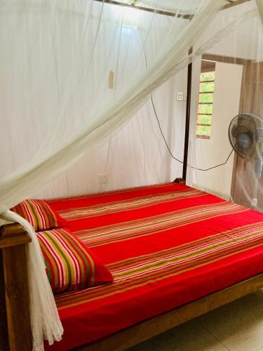 a red bed in a tent with a red comforter at Ameena Homestay in Tangalle