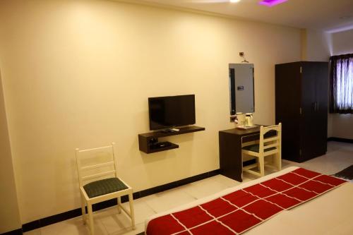 a living room with a tv and a chair and a table at Hotel Sparkling Pearl in Aurangabad